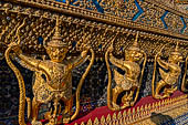 Bangkok Grand Palace,  Wat Phra Keow (temple of the Emerald Buddha). Golden garudas holding nagas support the external wall of the ubosot. 